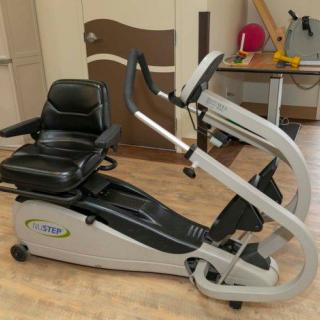 A seated exercise machine designed for cardio workouts, featuring pedals and handlebars.