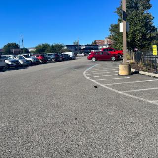 A view of a spacious parking lot filled with cars under a clear blue sky.