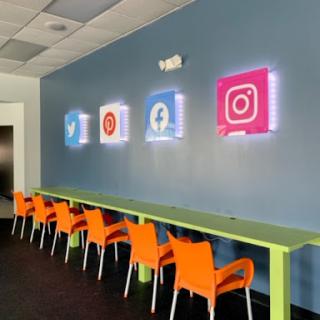 A vibrant workspace featuring illuminated social media icons and colorful seating.