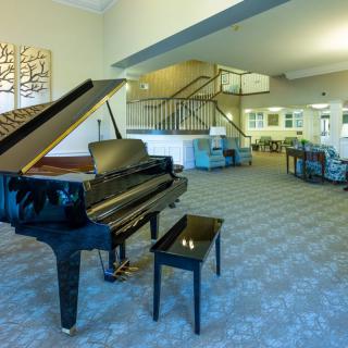 A spacious living room featuring a grand piano and modern furniture.