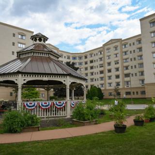 A decorated gazebo in front of a large residential building surrounded by greenery.