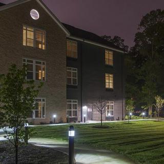 A well-lit building with trees and a pathway at night.