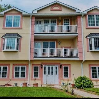 A charming residential building featuring multiple balconies and a well-maintained lawn.