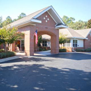 A brick building with a covered entrance and an American flag displayed in front.