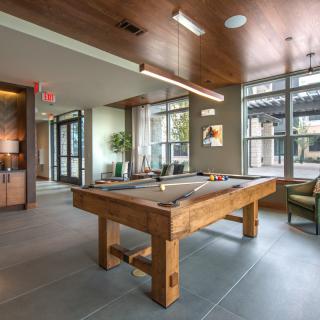 A modern game room featuring a wooden pool table and stylish seating.