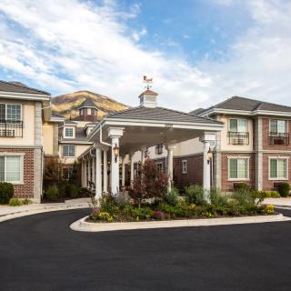 A modern residential building with a landscaped entrance and covered driveway.