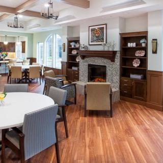 A cozy living and dining area featuring a fireplace, round table with chairs, and wooden shelves.