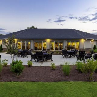 A spacious modern house with a well-lit patio and landscaped garden during the evening.