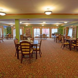 A spacious dining room with multiple tables and chairs arranged neatly under warm lighting.