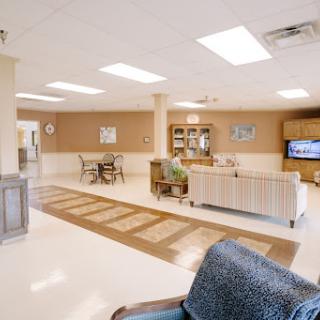 A spacious and well-lit lounge area featuring comfortable seating, a television, and dining arrangements.