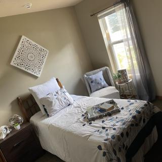 A cozy and modern bedroom with a single bed, decorative pillows, and natural light from the window.