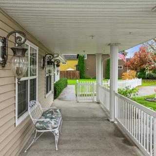 A cozy porch with a bench overlooking a yard and garden.
