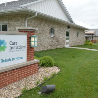 A healthcare facility with a sign reading 'Care Initiatives - Rehab to Home' displayed outside.