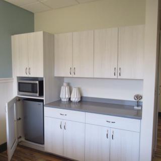 Modern kitchen area with white cabinets, a microwave, and decorative vases on the countertop.