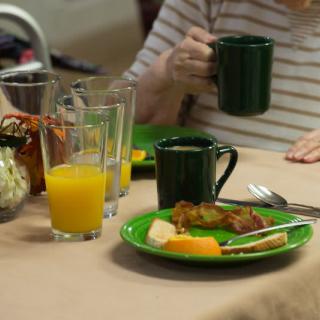 Breakfast setting with orange juice, coffee, and a plate of food.
