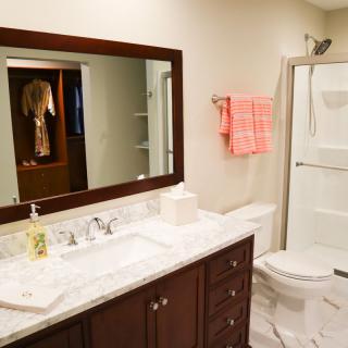 A modern bathroom with a large mirror, sink, toilet, and shower area.