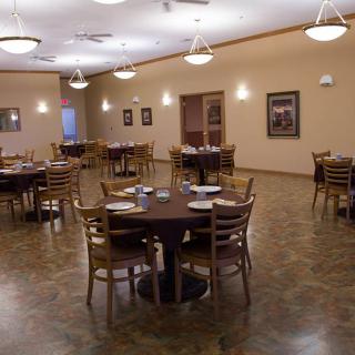An empty dining room with several round tables and chairs arranged neatly.