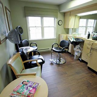 A cozy hair salon with styling chairs, a hair dryer, and a waiting area with magazines.