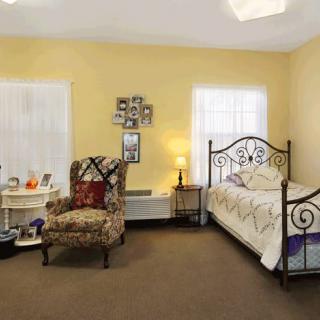 A cozy bedroom with a decorative chair, metal bed frame, and warm lighting.