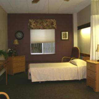 A cozy bedroom with a single bed, dresser, and window with blinds.