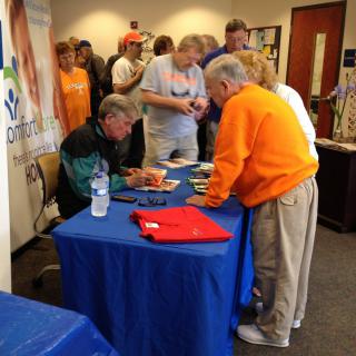 A book signing event with attendees gathered around a table for autographs.