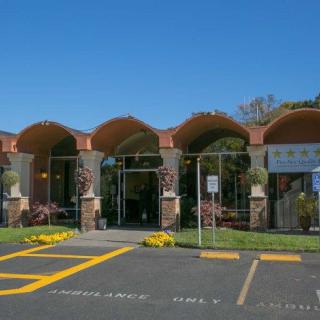 A building with arch-shaped entrances and a parking lot under a clear blue sky.