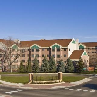 A residential apartment building with a landscaped front and clear blue sky.