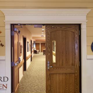 A corridor entrance featuring a wooden door leading to an interior hallway.