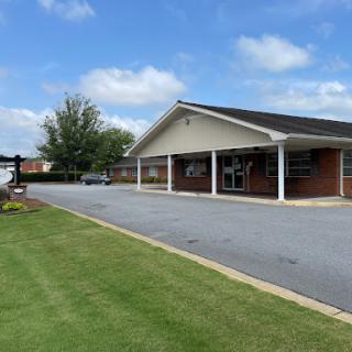 A view of a commercial building with a well-maintained lawn and clear blue skies.