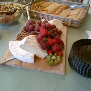 A cheese and fruit platter with grapes, strawberries, and crackers.