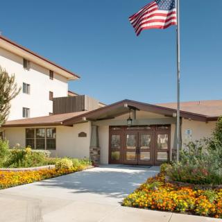 A building entrance with a garden and an American flag waving above.