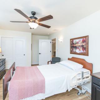 A cozy bedroom featuring a hospital bed, ceiling fan, and warm decor.