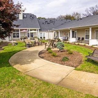 A well-maintained courtyard with a winding pathway, surrounded by benches and garden landscaping.