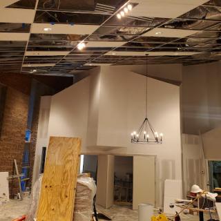 An interior space undergoing renovation with exposed ceiling panels and construction materials.