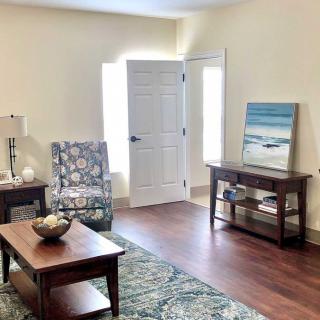 A cozy living room with modern furniture and a beach-themed artwork.