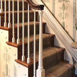 A traditional staircase with carpeted steps and a wooden handrail.