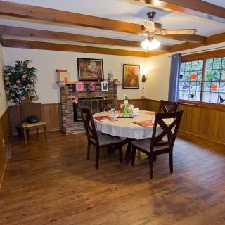 A cozy dining room with wooden floors, a table set for dining, and a fireplace adorned with decorations.
