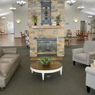 A cozy living room with sofas and armchairs arranged around a fireplace and coffee table.