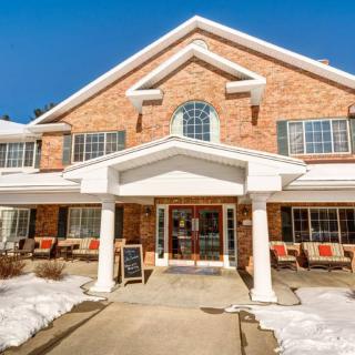 A brick building with a welcoming entrance surrounded by snow on a clear winter day.