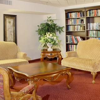 A cozy living room with elegant furniture, a wooden coffee table, and a bookshelf filled with books.