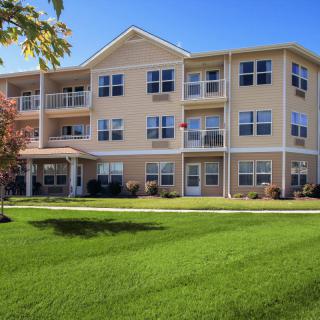 A multi-story residential apartment building with a well-maintained lawn.