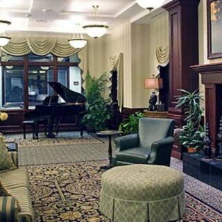 A cozy lobby area featuring elegant furniture, a grand piano, and a fireplace.