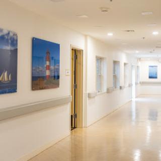 A well-lit hallway in a hospital featuring framed artworks on the walls.