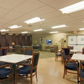 A spacious dining area with multiple tables and chairs under bright lighting.