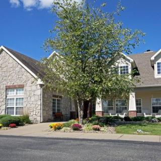 A suburban residential house with a tree in the front yard and a driveway.