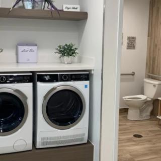 A modern laundry area with a washer and dryer next to a bathroom.