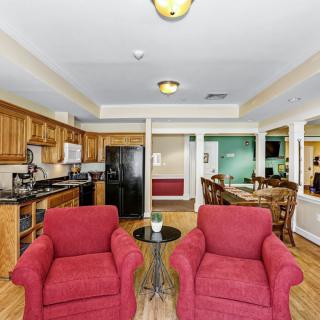 A modern open-concept living space featuring a kitchen, dining area, and two red armchairs in the foreground.