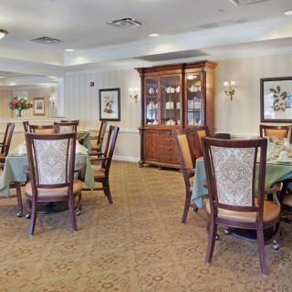 A well-furnished dining room featuring elegant chairs and tables, with a wooden cabinet and decor on the walls.
