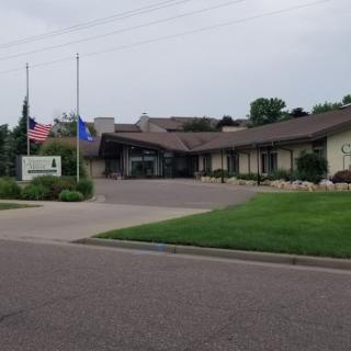 A clinic building with flags flying outside, surrounded by greenery.
