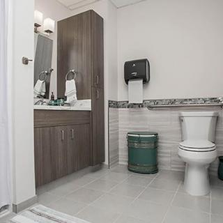 A clean and modern bathroom with a toilet, sink, and paper towel dispenser.